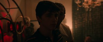 Movie still from “Hot Summer Nights” (2017), directed by Elijah Bynum – A young man is standing next to another man in a dark room; Close Up shot, Over the shoulder angle