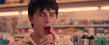 Movie still from “Hot Summer Nights” (2017), directed by Elijah Bynum – A young man holding a red lollipop in his mouth; Close Up shot, Low angle