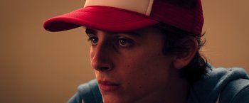Movie still from “Hot Summer Nights” (2017), directed by Elijah Bynum – A young man wearing a red and white hat; Extreme Close Up shot, Low angle