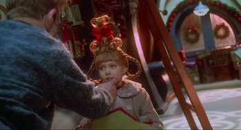 Movie still from “How the Grinch Stole Christmas” (2000), directed by Ron Howard – A young girl with long blonde hair and a red bow in her hair; Close Up shot, Over the shoulder angle