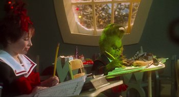 Movie still from “How the Grinch Stole Christmas” (2000), directed by Ron Howard – The grinch is sitting at a table writing on a piece of paper; Medium shot, Over the shoulder angle
