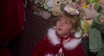 Movie still from “How the Grinch Stole Christmas” (2000), directed by Ron Howard – A young girl wearing a red cape and a candy hat; Close Up shot, Over the shoulder angle