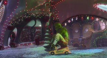 Movie still from “How the Grinch Stole Christmas” (2000), directed by Ron Howard – A person sitting on a toy car in a room with christmas lights; Extreme Wide shot, High angle