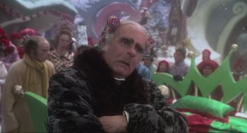 Movie still from “How the Grinch Stole Christmas” (2000), directed by Ron Howard – An older man with hair curlers in his hair; Close Up shot, Over the shoulder angle