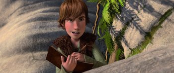 Movie still from “How to Train Your Dragon” (2010), directed by Chris Sanders – A young boy is holding a notebook and pen; Medium shot, High angle