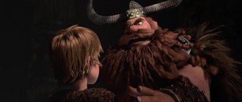 Movie still from “How to Train Your Dragon” (2010), directed by Chris Sanders – A man with long hair and a horned hat is talking to a young boy; Close Up shot, Over the shoulder angle