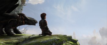 Movie still from “How to Train Your Dragon 2” (2014), directed by Dean DeBlois – A person sitting on top of a rock next to a dragon; Wide shot, Over the shoulder angle