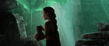 Movie still from “How to Train Your Dragon 2” (2014), directed by Dean DeBlois – A woman holding a teddy bear while standing in front of a cave; Medium shot, Over the shoulder angle