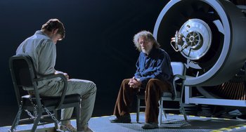 Movie still from “Hulk” (2003), directed by Ang Lee – A man sitting on a chair next to another man; Wide shot, Over the shoulder angle