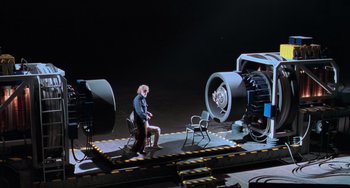 Movie still from “Hulk” (2003), directed by Ang Lee – A man sitting on a chair in front of an airplane; Extreme Wide shot, High angle