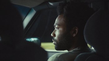 Movie still from “Atlanta” (2016), created by Donald Glover – A person sitting in a car looking out of the window; Close Up shot, Over the shoulder angle