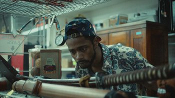 Movie still from “Atlanta” (2016), created by Donald Glover – A man wearing a hat looking down at a baseball bat; Close Up shot, Over the shoulder angle