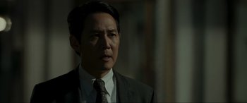Movie still from “Hunt” (2022), directed by Lee Jung-jae – A person wearing a suit and tie; Close Up shot, Over the shoulder angle