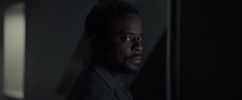 A man with a beard is standing in a dark room