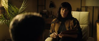 Movie still from “Hypnotic” (2023), directed by Robert Rodriguez – A woman sitting on a chair in a living room; Medium shot, Over the shoulder angle