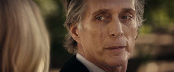 Movie still from “Hypnotic” (2023), directed by Robert Rodriguez – An older man wearing a suit and tie looking at the camera; Close Up shot, Over the shoulder angle