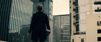 Movie still from “Hypnotic” (2023), directed by Robert Rodriguez – A man in a black jacket is holding a book; Wide shot, Low angle