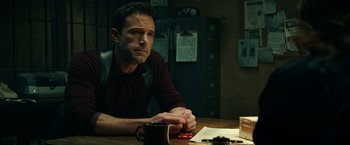 Movie still from “Hypnotic” (2023), directed by Robert Rodriguez – A man sitting at a table in a dark room; Medium shot, Over the shoulder angle