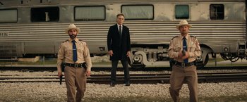 Movie still from “Hypnotic” (2023), directed by Robert Rodriguez – A man standing next to a train on a train track; Wide shot, Low angle