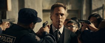 Movie still from “Hypnotic” (2023), directed by Robert Rodriguez – A man in a suit and tie holding a gun while another man holds a gun; Close Up shot, Over the shoulder angle