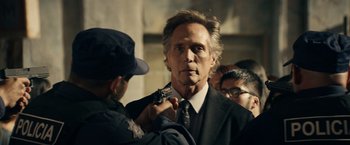 Movie still from “Hypnotic” (2023), directed by Robert Rodriguez – A man in a suit and tie holding a gun in his hand; Close Up shot, Over the shoulder angle