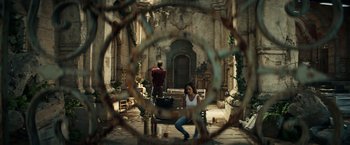 Movie still from “Hypnotic” (2023), directed by Robert Rodriguez – A woman crouching down in front of a man; Wide shot, High angle