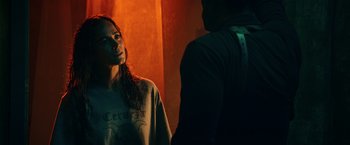 Movie still from “Hypnotic” (2023), directed by Robert Rodriguez – A woman standing next to a man in a dark room; Medium shot, Over the shoulder angle