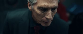 Movie still from “Hypnotic” (2023), directed by Robert Rodriguez – An older man wearing a black shirt and a red tie; Close Up shot, Low angle