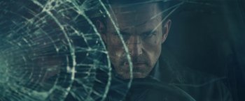 Movie still from “Hypnotic” (2023), directed by Robert Rodriguez – A person looking through a broken glass window; Close Up shot, Over the shoulder angle