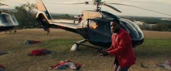 Movie still from “Hypnotic” (2023), directed by Robert Rodriguez – A man in a red jacket standing in front of a helicopter; Medium shot, High angle