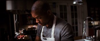 Movie still from “I Am Legend” (2007), directed by Francis Lawrence – A man wearing an apron in a kitchen looking down; Close Up shot, High angle