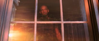Movie still from “I Am Legend” (2007), directed by Francis Lawrence – A man looking out of a window at sunset; Medium shot, Low angle