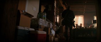 Movie still from “I Am Legend” (2007), directed by Francis Lawrence – A man standing next to a pile of boxes in a room; Wide shot, Low angle