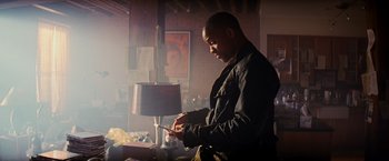 Movie still from “I Am Legend” (2007), directed by Francis Lawrence – A man sitting in front of a lamp in a room; Medium shot, Low angle