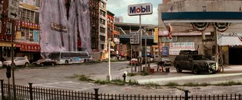 Movie still from “I Am Legend” (2007), directed by Francis Lawrence – An empty city street with an old gas station sign on the corner; Extreme Wide shot, High angle