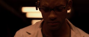 Movie still from “I Am Legend” (2007), directed by Francis Lawrence – A person wearing glasses and a white shirt; Close Up shot, Over the shoulder angle