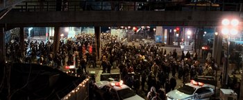 Movie still from “I Am Legend” (2007), directed by Francis Lawrence – A crowd of people gathered in a parking lot at night; Extreme Wide shot, High angle