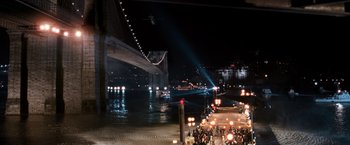 Movie still from “I Am Legend” (2007), directed by Francis Lawrence – A crowd of people standing on a sidewalk next to a river at night; Extreme Wide shot, High angle