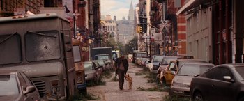 Movie still from “I Am Legend” (2007), directed by Francis Lawrence – A man walking a dog down a street; Wide shot, High angle