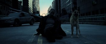 Movie still from “I Am Legend” (2007), directed by Francis Lawrence – A man sitting on the ground next to a dog on the street; Wide shot, High angle