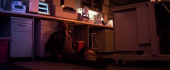 Movie still from “I Am Legend” (2007), directed by Francis Lawrence – A man sitting on the ground in a kitchen; Wide shot, High angle