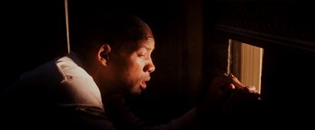 Movie still from “I Am Legend” (2007), directed by Francis Lawrence – A person sitting in the dark; Close Up shot, Low angle