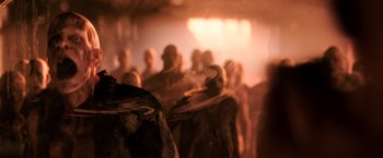 Movie still from “I Am Legend” (2007), directed by Francis Lawrence – A group of people standing in front of a stage; Medium shot, Over the shoulder angle