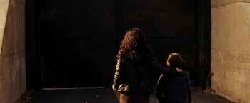 Movie still from “I Am Legend” (2007), directed by Francis Lawrence – A woman and a child are holding hands in the dark; Medium shot, Over the shoulder angle