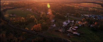 Movie still from “I Am Legend” (2007), directed by Francis Lawrence – An aerial view of a rural area with buildings and trees in the background; Extreme Wide shot, High angle