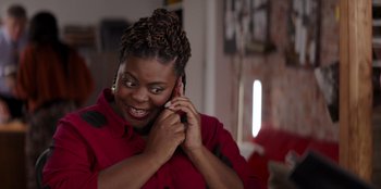Movie still from “I Believe in Santa” (2022), directed by Alex Ranarivelo – A woman talking on a cell phone while wearing a red shirt; Close Up shot, Over the shoulder angle