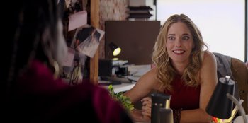 Movie still from “I Believe in Santa” (2022), directed by Alex Ranarivelo – A woman sitting in front of a computer smiling for the camera; Close Up shot, Over the shoulder angle