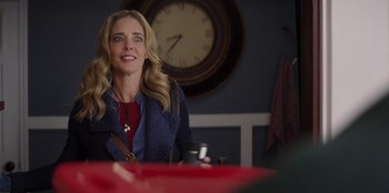 Movie still from “I Believe in Santa” (2022), directed by Alex Ranarivelo – A woman sitting at a table with a cup of coffee in front of a clock on the wall; Close Up shot, Over the shoulder angle