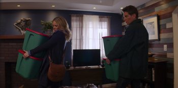Movie still from “I Believe in Santa” (2022), directed by Alex Ranarivelo – A man and a woman carrying boxes in a living room; Medium shot, Low angle