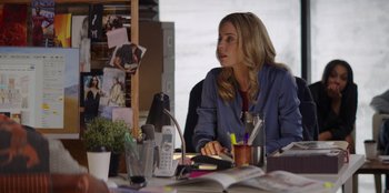 Movie still from “I Believe in Santa” (2022), directed by Alex Ranarivelo – A woman sitting at a table with a book and phone; Medium shot, Over the shoulder angle